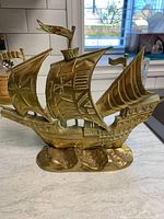 Front and side views of the vintage brass sail ship showing detailed sails, flags, and wave base
