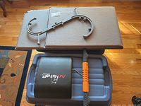 Amstaff Fitness ab roller bar with cushioned pad and orange foam grips resting on plastic tubs