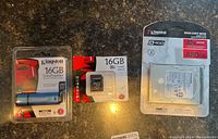 Three Kingston branded items arranged side by side: a 16GB USB 3.0 flash drive in sealed packaging, a 16GB microSD card with adapter in sealed packaging, and a 480GB solid state drive in blister packaging.