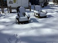 Two wooden Muskoka chairs outdoors covered with snow, showing worn wood and weathered condition.