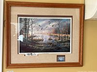 Framed print by Ken Zylla showing a nature scene with flying birds over a marsh area, mounted and framed under glass.