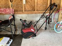 King Canada electric snow thrower positioned inside a garage showing entire machine with wheels and handlebars.