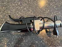 Full view of the sous vide cooker showing black handle, stainless steel body and coiled power cord.