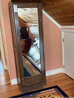 Front view of tall wooden wardrobe cabinet showing full-length mirror on door and dark wood finish.