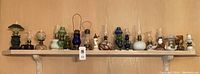 Shelf displaying 24 assorted small hurricane lamps in various colors and styles
