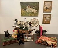 Overall group shot of assorted dog collectibles arranged on table against wall.