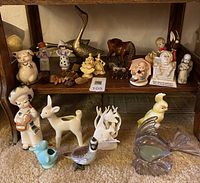 Overview of many figurines arranged on shelf and floor showing variety and condition.