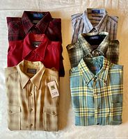 Six folded Pendleton shirts arranged in two columns, showing variety of plaid and solid colors typical of wool and cotton fabrics.