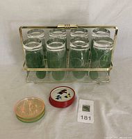 Full set with 6 green decorative vintage cocktail glasses in gold-tone metal holder, plus two sets of coasters in front of holder.