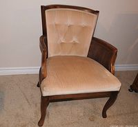 Front view of the Queen Anne armchair showing beige tufted upholstery, cane arm sides, and dark wood frame with cabriole legs.