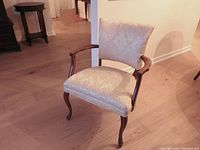 Ivory white Louis XV-style accent armchair with carved cabriole legs, visible damask upholstery detail, wooden arms, and a curved backrest.