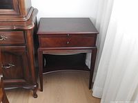 Full view of dark wood Bombay Company nightstand with drawer and lower shelf.