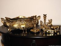 Wide view showing all brass items together: jardiniere, dachshunds, candle holders, small holders, and key holder.