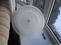 Top down view of circular frosted glass ceiling light cover showing textured starburst, diamond and dot pattern details and central finial.