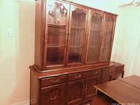 Full view of the sideboard and hutch together showing wood finish, handles, and glass doors.