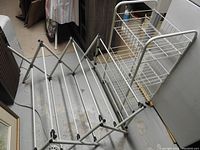 Foldable white metal drying rack viewed from the side showing multiple rods used for hanging laundry
