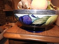 Side view of Moorcroft bowl showing exterior fruit decoration with artificial fruit inside