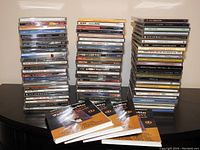 Stacked assorted music CDs and Dean Martin DVDs with their booklets visible.