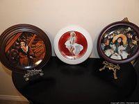 Three framed limited edition decorative plates: two featuring Scarlett O'Hara from Gone with the Wind in dark wood frames, one with Marilyn Monroe in a white frame.