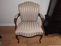 Front view of the armchair showing striped satin-like upholstery with wood armrests and legs.