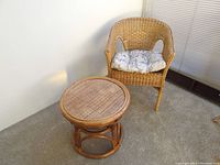 Full view of the bamboo and wicker round tray table alongside the rattan open barrel chair with cushion.