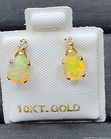 Front view of the opal and moissanite drop earrings on white 10k gold display card showing the prong set gemstones.