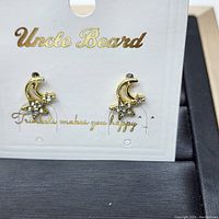 Front view of pair of gold plated earrings with crescent moon and clear cubic zirconia stones on Uncle Beard branded card