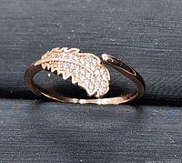 Close-up front angle of rose gold plated adjustable ring featuring leaf design with clear cubic zirconia inlay.