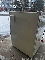 Side view of small beige bar fridge showing door and silver handle