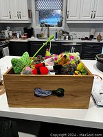 Wooden box filled with assorted dog toys on kitchen counter.