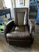 Front view of brown leather recliner chair showing damage on seat and armrests