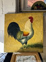 Frontal photo showing single square canvas with painted rooster on yellow textured background.