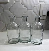 Front view of the three small clear glass vases showing their similar rounded shape and flared rims.