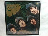 Front view of the framed Rubber Soul album cover showing the band members and title in large brown font.