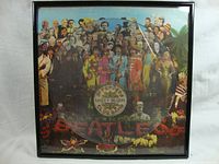 Front view of the framed Beatles Sgt. Peppers Lonely Hearts Club Band vinyl picture disc with colorful artwork and the vinyl disc centered on the album cover.