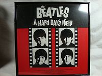 Front view of The Beatles A Hard Days Night album in a black frame showing album art with portraits of the band members.