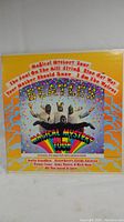 Front cover of gatefold jacket featuring psychedelic design and photo of Beatles costumed figures