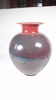 Front view of the round pottery vase showing the gradient glaze from red neck to dark body.