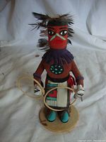 Front view of the Native American Kachina Hoop Dancer figurine showing painted face, purple collar, and holding hoops.