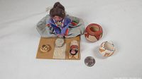 Full view of Native American woman figurine with baby and two miniature pottery pots alongside a quarter for size reference.