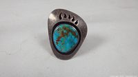 Front view of silver ring with turquoise stone in bear paw design.