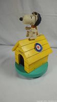 Front view of Snoopy in aviator outfit on yellow doghouse music box