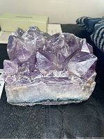 Front view of amethyst cluster showing multiple purple crystals and white base.