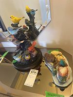 Overview of both porcelain birds on wood stand and ceramic ducks on table with mirror reflection