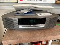Front view of Bose Wave Music System showing digital clock display at 12:51, with CD slot and grille.