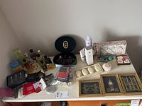 Full lot overview showing perfume and cologne bottles, bath soaps, and framed London metallic prints by L Kersh.