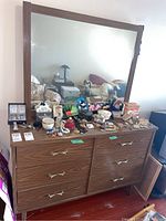 Front view of the dresser with mirror, showing items on top and the dresser's surface and handles