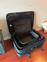 Open large black suitcase showing interior compartments and zippers