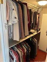 Closet rack with assorted men's dress pants and shirts hanging on hangers