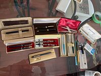 Overview of all pens, pen sets in branded boxes and accessories on glass table